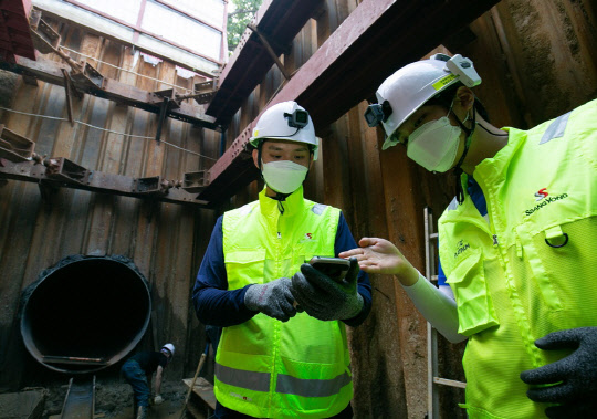 액션캠과 위치태그 등이 장착된 스마트 안전모를 착용하고 스마트폰으로 현장을 확인하는 쌍용건설 건설현장 작업자의 모습. <쌍용건설 제공>